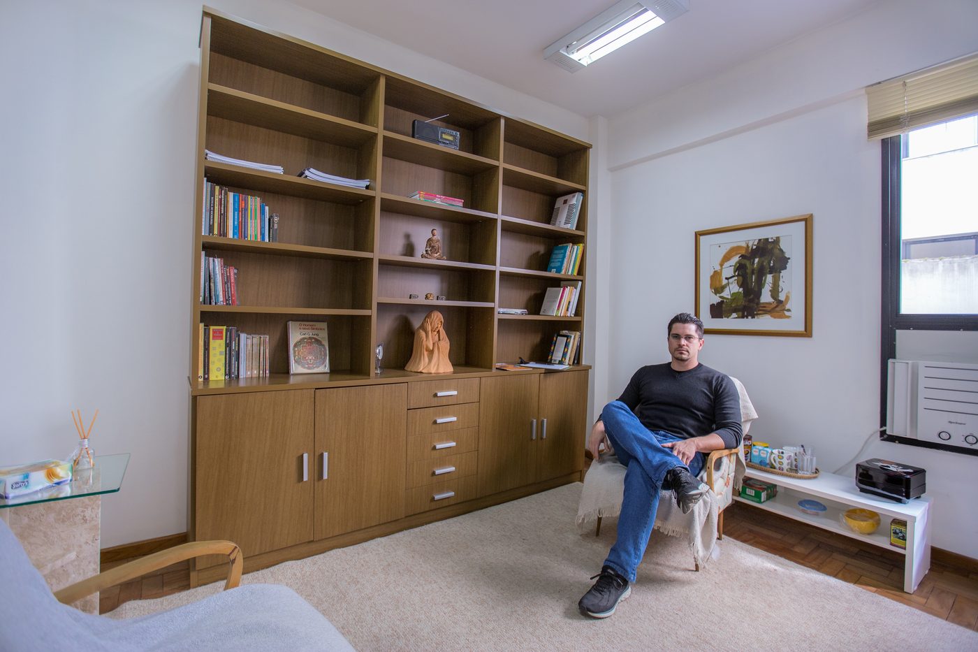Sala do consultório de psicologia em Canela, com estante e poltronas